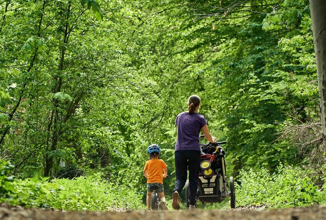 Mutter mit Kinderwagen und Kind im Wald